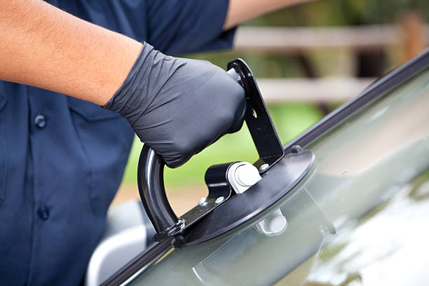 Auto glass technician carefully installing a windshield using professional safety equipment